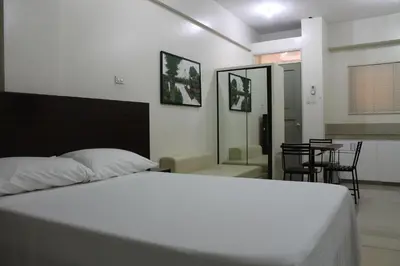 a bedroom with a white bed and a table and chairs at RESIDENCIA SAN VICENTE - PASAY -Budget Hotel in Manila