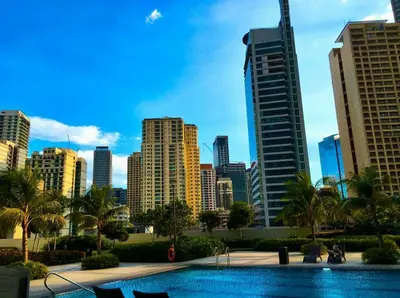a city skyline with a swimming pool in front of a city at Linda's Condo in Manila