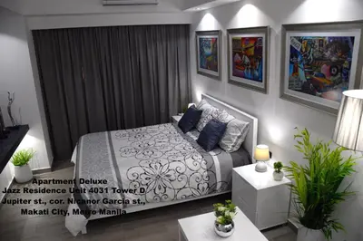 a bedroom with a bed and some paintings on the wall at Jazz Makati Luxury Apartment in Manila
