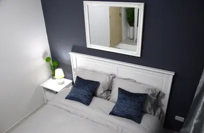 a mirror above a bed with two blue pillows at Jazz Makati Luxury Apartment in Manila