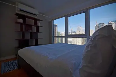 a bedroom with a bed and a large window at Victoria SOHO Suites in Manila