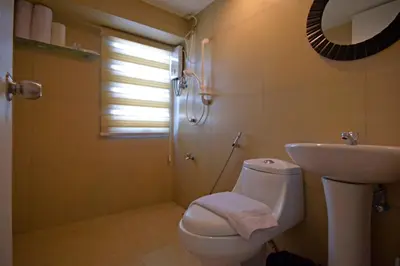a bathroom with a toilet and a sink and a shower at Victoria SOHO Suites in Manila