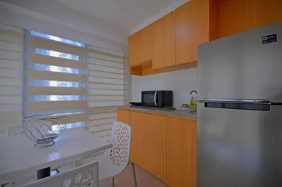 a kitchen with a white refrigerator and wooden cabinets at Victoria SOHO Suites in Manila