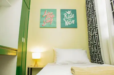 a bedroom with a bed with two pictures on the wall at Nomads MNL Backpackers Homestay - near Airport in Manila