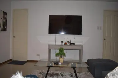 a living room with a table and a tv on a wall at Affordable Makati APT in Manila
