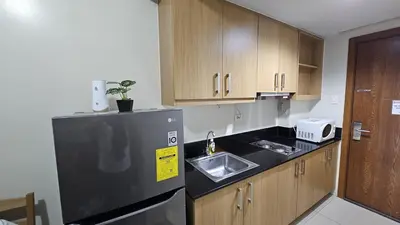 a kitchen with a black refrigerator and a sink at The Palawanos Home at Shell Residences in Manila