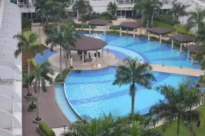 an overhead view of a large swimming pool with palm trees at The Palawanos Home at Shell Residences in Manila
