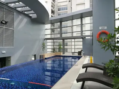 a swimming pool in a building with two chairs at Valero Grand Suites by Swiss-Belhotel in Manila