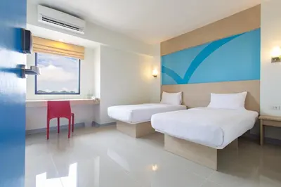a hotel room with two beds and a red chair at Hop Inn Hotel Makati Avenue Manila in Manila