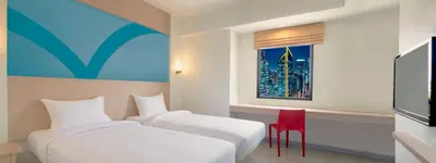 a hotel room with two beds and a red chair at Hop Inn Hotel Makati Avenue Manila in Manila