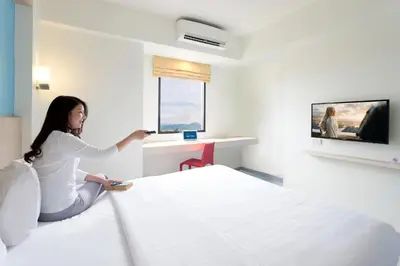 a woman sitting on a bed in a hotel room at Hop Inn Hotel Makati Avenue Manila in Manila