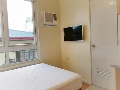 a small bedroom with a bed and a window at The Leaf House in Manila