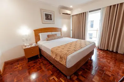 a bedroom with a large bed and a wooden floor at City Garden Suites Manila in Manila