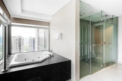 a bathroom with a tub and a glass shower at Ascott Makati in Manila