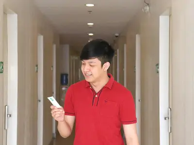 a man in a red shirt holding a remote control at Go Hotels Ermita, Manila in Manila