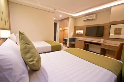 a hotel room with two beds and a television at Crown Regency Hotel Makati in Manila