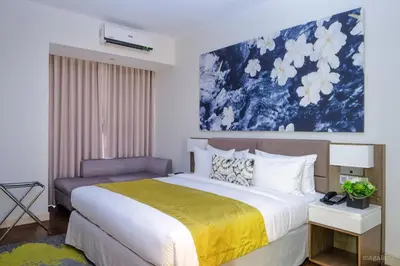 a bedroom with a large bed with a yellow blanket at Citadines Millennium Ortigas Manila in Manila