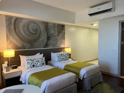two beds in a hotel room with a painting on the wall at Citadines Millennium Ortigas Manila in Manila