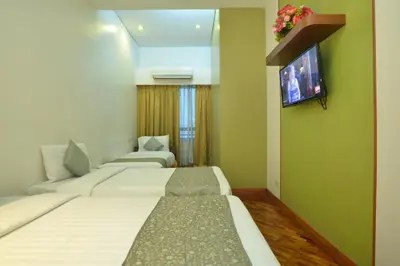 a hotel room with three beds and a flat screen tv at The Malayan Plaza Hotel in Manila