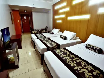 a row of four beds in a hotel room at Jupiter Suites in Manila