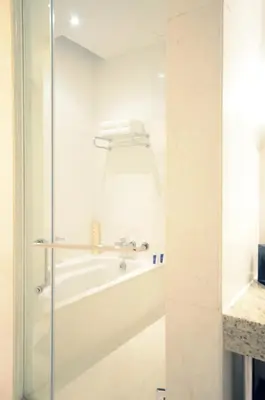 a bathroom with a tub and a glass shower door at New Coast Hotel Manila in Manila