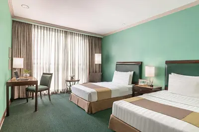 a hotel room with two beds and a desk at Makati Palace Hotel in Manila