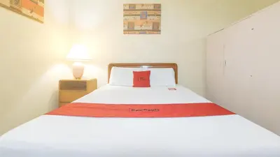 a bedroom with a bed with a red pillow on it at RedDoorz at Broadway Court Apartelle Quezon City in Manila