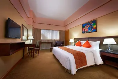 a hotel room with a large bed and a desk at Berjaya Makati Hotel in Manila