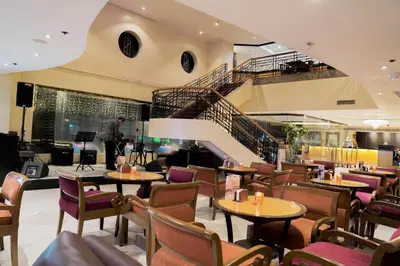 a restaurant with tables and chairs and a staircase at Berjaya Makati Hotel in Manila