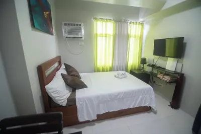 a bedroom with a bed with white sheets and a television at Yong's Place at Vista Residences Taft in Manila