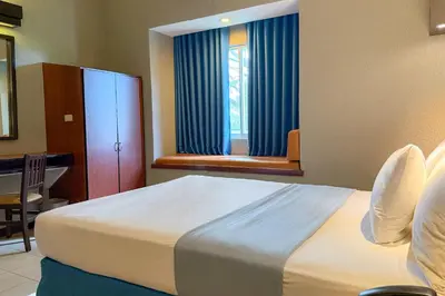 a bedroom with a bed and a table and a window at Microtel by Wyndham Eagle Ridge in General Trias