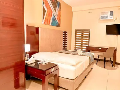 a bedroom with a bed and a table and a desk at Casa Bocobo Hotel in Manila