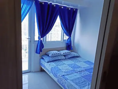 a bedroom with a bed with blue curtains and a window at Light Residences 1BR Apartment Balcony in Manila
