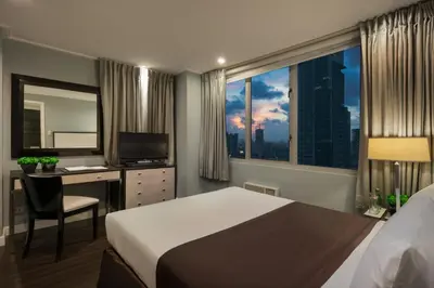 a bedroom with a bed and a desk and a window at Astoria Plaza in Manila