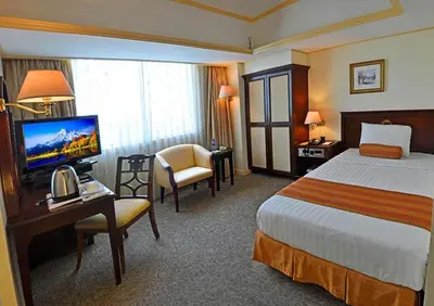 a hotel room with a bed and a desk and a television at Networld Hotel Spa and Casino in Manila