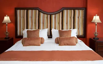 a bedroom with a large bed with orange walls at Hotel Celeste Makati in Manila