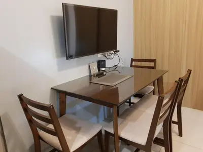 a dining room table with chairs and a television on the wall at Breeze Residences by CS Luxe in Manila