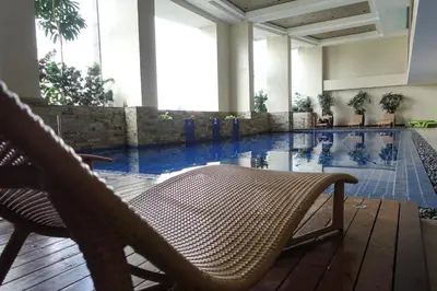 a hotel lobby with a pool and a chair at KL Executive Greenbelt (KLX) in Manila