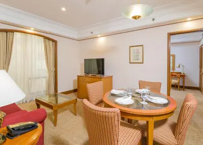 a living room with a table and chairs and a television at Richmonde Hotel Ortigas, Manila in Manila