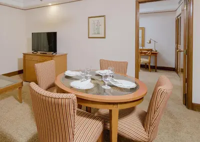 a dining room with a table with chairs and a television at Richmonde Hotel Ortigas, Manila in Manila