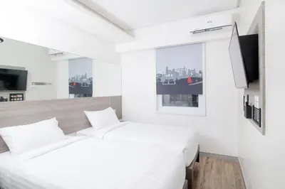 a white bedroom with a bed and a tv at Red Planet Manila Bay in Manila