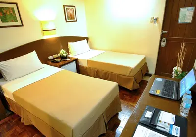 a hotel room with two beds and a laptop on a table at Fersal Hotel - Manila in Manila