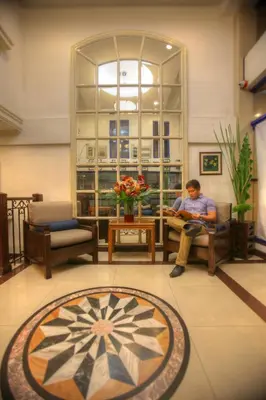 a man sitting in a chair in a lobby at Fersal Hotel - Manila in Manila