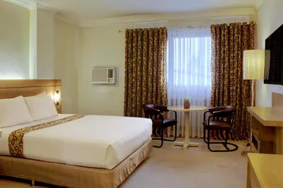 a hotel room with a bed and a table at Rothman Hotel in Manila