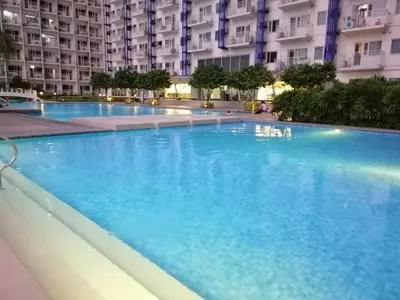 a large swimming pool with blue water in front of buildings at SNAPz Staycation @ Jazz Residences in Manila