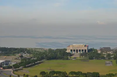 a building with a large field in front of the ocean at Jovic's Condo at Breeze Residences. in Manila