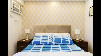 a bedroom with a bed with blue and white pillows at Grand Apartment near BGC in Manila