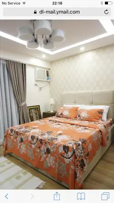 a bedroom with a large bed with an orange blanket at Grand Apartment near BGC in Manila