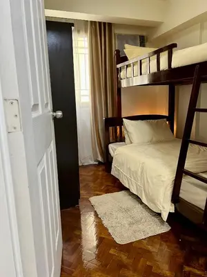 a bedroom with two bunk beds and a wooden floor at East Ortigas Mansions by MA in Manila