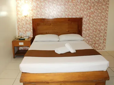 a bedroom with a bed with two towels on it at Rosas Garden Hotel in Manila